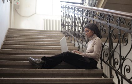 woman-sitting-on-staircase-while-using-her-laptop-3876811
